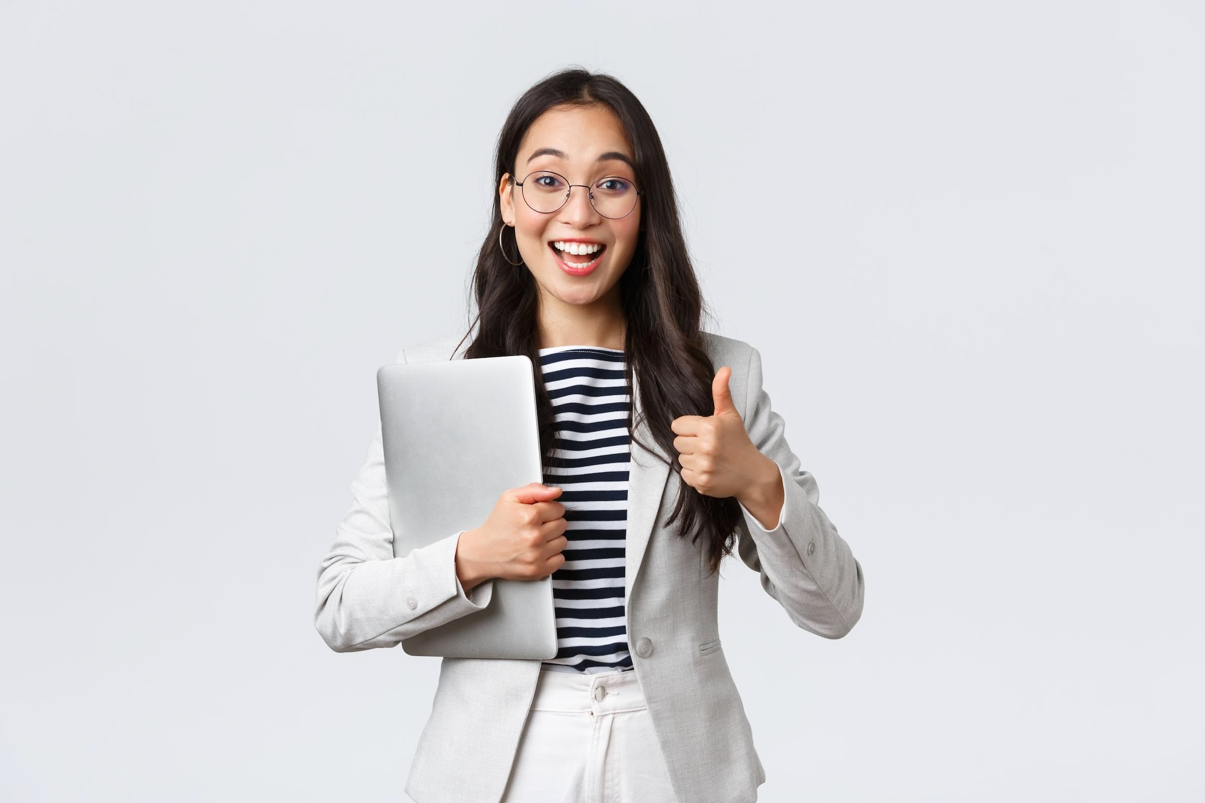Business, finance and employment, female successful entrepreneurs concept. Young confident businesswoman in glasses, showing thumbs up gesture, hold laptop, guarantee best service quality